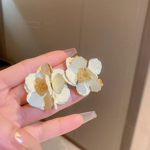 Macro shot of 3D white enamel flower earrings with gold-plated edges and stamen