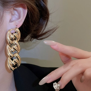 Close-up of a model wearing a polished gold chunky chain earring in a luxury fashion style