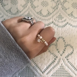 Baroque pearl ring set with a star charm and square silver band on lace background