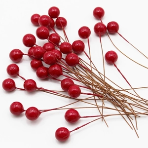Vibrant red artificial berry stems with glossy finish on a clean white background