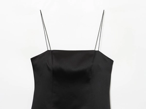 Détail du tissu en satin noir lisse et des fines bretelles de la robe bordée de dentelle