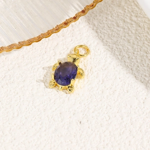 Detailed macro view of a gold turtle pendant with a deep purple gemstone inlay