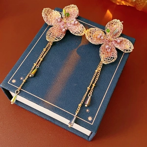Detailed macro view of vintage pink butterfly earrings with gold chain tassels