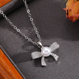 Close-up of bowknot necklace featuring a white pearl and sparkling crystals on velvet