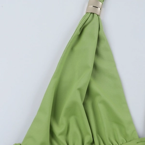 Vue macro du tissu vert herbe avec attache cylindrique en métal doré et détail de bride