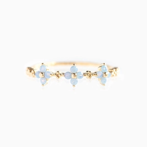 Close-up of golden 18K ring with light blue flowers and zircon stones on white background