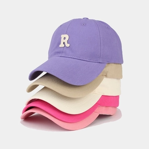 Dettaglio di berretti da baseball in cinque colori con toppe ricamate con lettera R