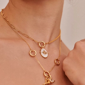 Layered gold necklace set featuring starburst pendant and circle accents on a model