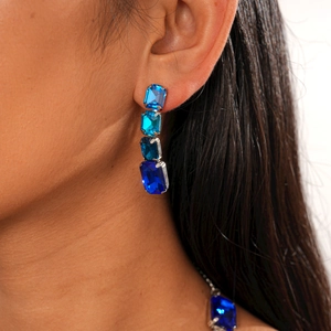Close-up of long drop earrings with four rectangular blue gradient gemstones on model