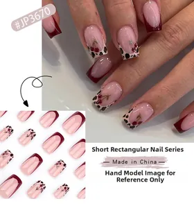 Détail de faux ongles rouges French avec motifs léopard et cerises élégants