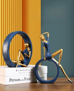 Artistic resin girl figurine in deep blue and gold finish reading on a stack of books