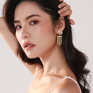 Elegant gold pearl tassel earrings with shimmering crystals on a female model