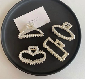Set of four pearl hair claws in geometric shapes displayed on a black plate