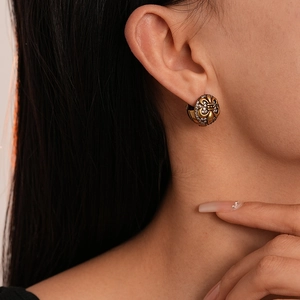 Close-up of vintage gold fleur-de-lis earrings with white zircons worn by a model