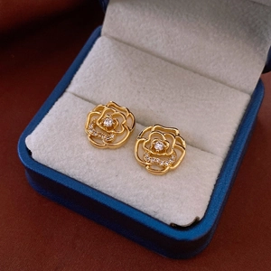 Macro detail of golden camellia flower stud earrings with shimmering zircon insets