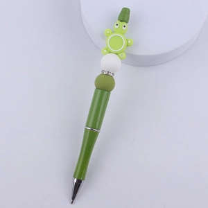 Detail of green DIY beaded pen featuring a cute turtle charm with sparkling rhinestones