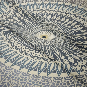 Détail d'une tapisserie mandala bohème avec motifs tissés bleu-gris et texture du tissu