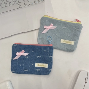 Dettaglio di portamonete in denim con fiocchi ricamati, nastro rosa e logo Sezakka