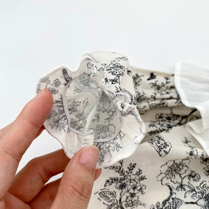 Close-up of elastic ruffled cuffs with black and white floral print on baby bodysuit