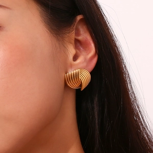 Detailed view of 18K gold plated fan-shaped textured earrings worn by a model