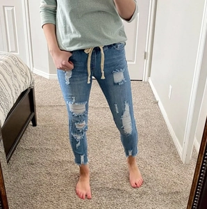 High-waisted ripped jeans with elastic drawstring waist and distressed details