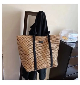 Detail of a beige woven straw tote bag with black rope handles on a black blazer