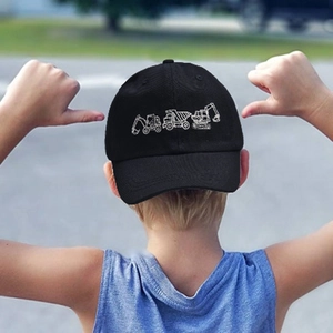 Kids black baseball cap featuring white excavator embroidery in an outdoor setting