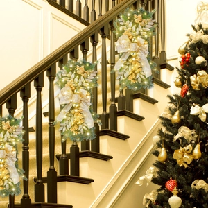 Detail of glowing Christmas swags with warm LED lights and gold bows on stair railings