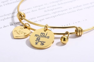 Macro view of adjustable gold heart charm bracelet with Love and mi mama engravings
