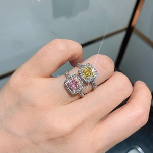 Macro view of halo-set rings with pink and yellow square stones on model's hand