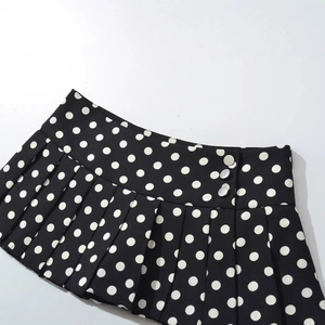 Mini-jupe plissée taille haute à pois noirs et blancs avec boutons latéraux