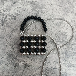 Detailed grid weave of black and silver beaded mini bag with silver chain strap