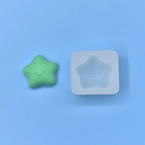 Detail of star-shaped pig silicone mold and a green finished resin craft on blue surface