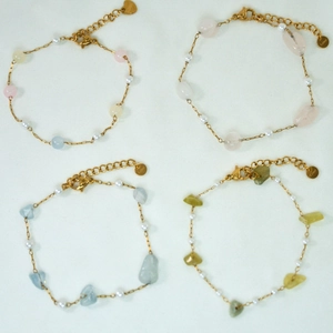 Macro view of stainless steel gold bracelets with natural stones and white pearls