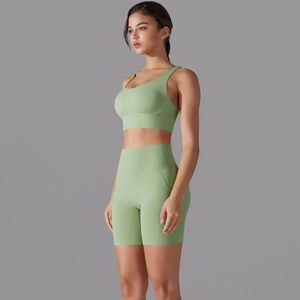 Vista laterale del set da yoga verde chiaro con pantaloncini a vita alta e reggiseno sportivo