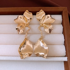 Vue détaillée des boucles d'oreilles fleurs dorées avec texture brossée et pétales 3D
