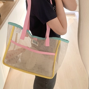 Detail of multi-color mesh tote bag with pink handles and blue trim for beach travel