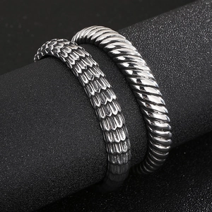 Macro detail of retro dragon scale relief and polished twist texture on men's steel rings