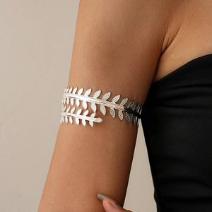 Detailed close-up of a silver metal leaf upper arm cuff bracelet on a model's arm