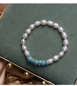 Close-up of pearl bracelet with blue turquoise beads on dark green velvet background