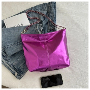 Top-down view of metallic purple tote bag with gold chain strap and stylish denim accessories