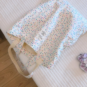 Detailaufnahme der weißen Stofftasche mit bunten Punkten und gewebtem Etikett