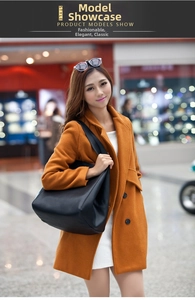 Detail of a large black pebbled leather tote bag paired with an orange wool coat
