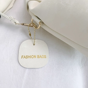 Minimalist white pleated hobo bag with gold hardware and fashion tag detail