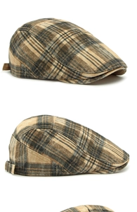 Detailed side view of British plaid flat cap with adjustable metal buckle on textured fabric