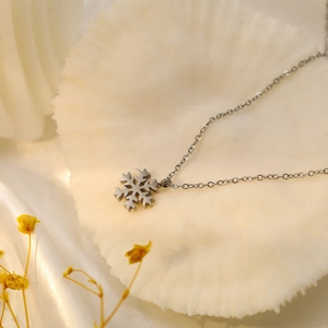 Silver snowflake pendant necklace in 18k gold plated stainless steel on white shell