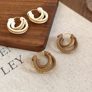Detail of 18k gold plated double hoop earrings in cream and brown on wooden blocks