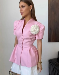 Détail du haut à basque rose avec fleur 3D et élégantes manches bouffantes