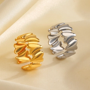 Polished gold and silver stainless steel heart rings on champagne silk background