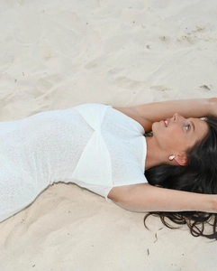 Détail d'une robe blanche sans manches en maille avec nœud torsadé sur la plage